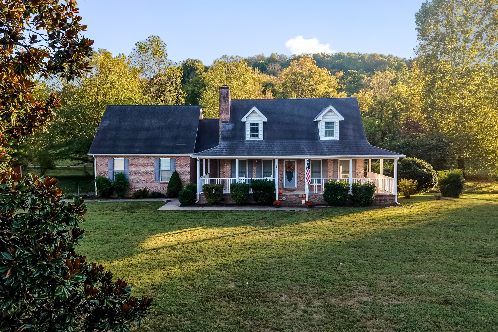 A welcoming porch, autumn trees, and the warmth of a home lived in. Photographed from the garden to the landscape above.