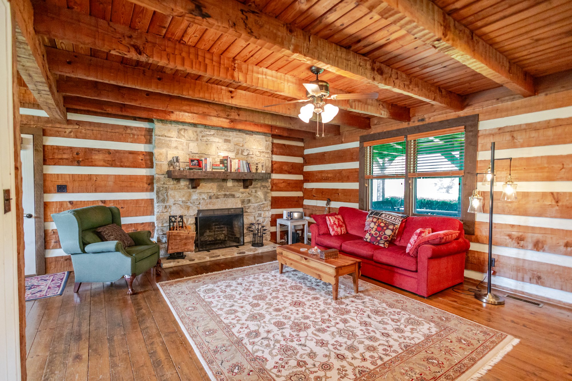 Guest cabin living room with timber walls and stone fireplace