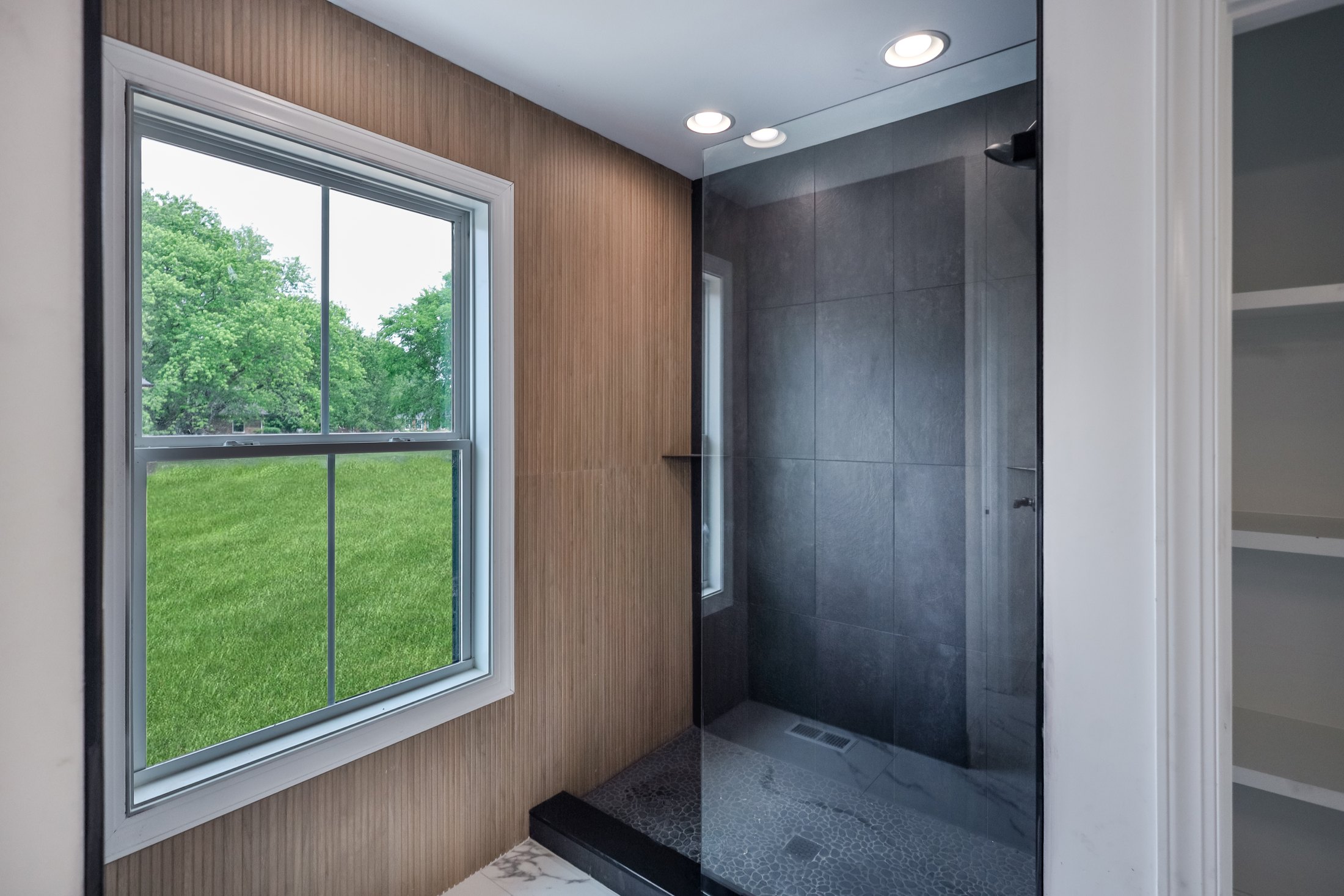 Wood-toned shower beside a garden-facing window