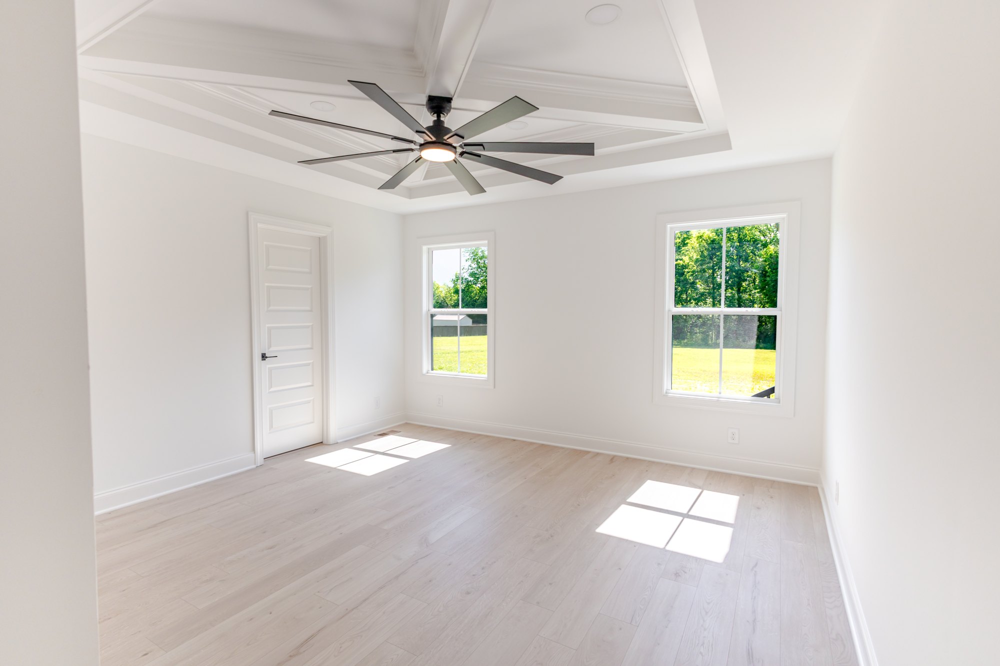 Bright bedroom with tray ceiling and tall windows