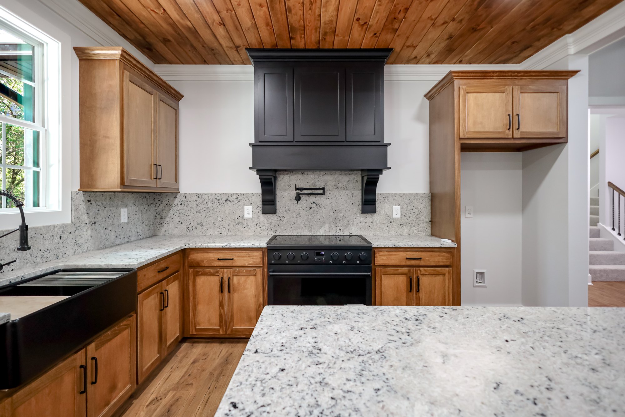 Wood kitchen cabinetry and dark range hood